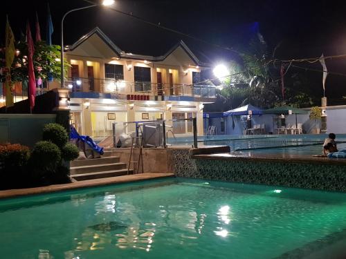 - une piscine en face d'une maison la nuit dans l'établissement EDUARDO'S RESORT, à Calapan