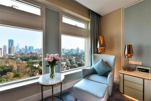 a room with a chair and a window with a vase of flowers at Radisson Collection Hotel, Xing Guo Shanghai in Shanghai