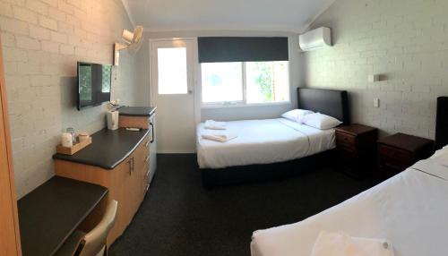 a hotel room with two beds and a desk and a room at Bateau Bay Hotel in Bateau Bay
