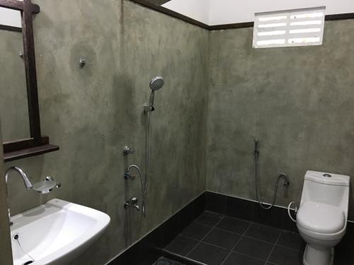 a bathroom with a toilet and a sink at Peacock Riverside in Udawalawe