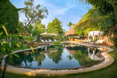 una piscina en un complejo con sillas y árboles en Navutu Dreams Resort & Wellness Retreat, en Siem Reap