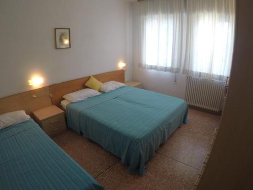 una camera d'albergo con due letti e due finestre di Casa Francesca - Agenzia Cocal a Caorle