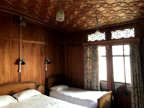 a bedroom with two beds in a room with wooden walls at Butts Clermount Houseboat in Srinagar