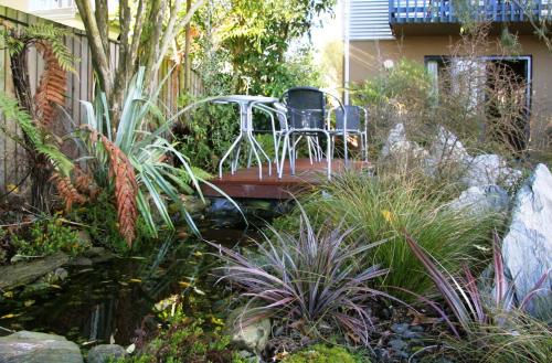 two chairs sitting on a wooden bridge over a pond at Sherborne Motor Lodge in Christchurch
