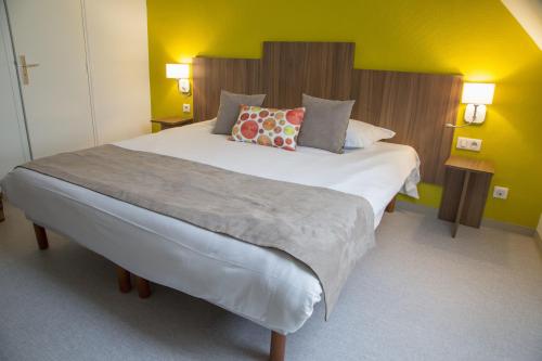a bedroom with a large bed in a room with yellow walls at Logis Hôtel Chaptal, Amboise in Amboise