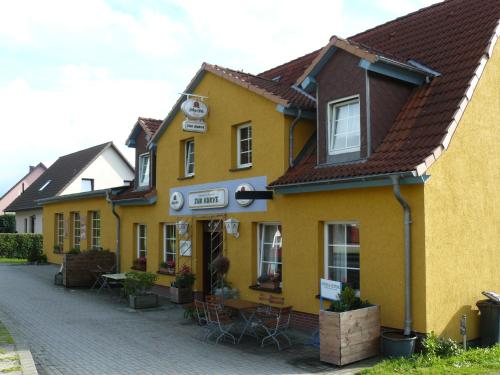 a yellow building with tables and chairs on a street at Pension bei Stralsund in Prohn