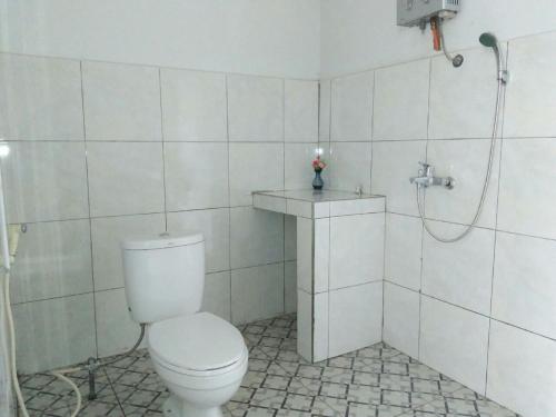 a white bathroom with a toilet and a shower at CF Komodo Hotel in Labuan Bajo