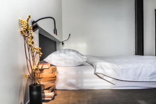 a bedroom with a bed and a lamp and books at Book a Bed Poshtel - SHA Plus in Phuket Town