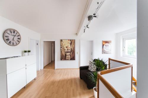 a white living room with a clock on the wall at SOVA Pension Fuldatal in Fuldatal