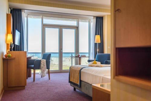a hotel room with a bed and a view of the ocean at Strand-Hotel Hübner in Warnemünde