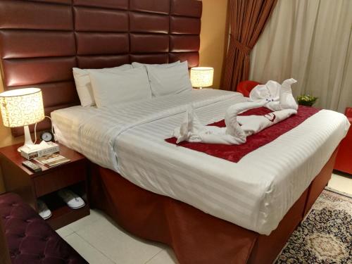 een hotelkamer met een groot bed met 2 personen in handdoeken bij فندق الأصيل ألوان الفندقية in Mekka