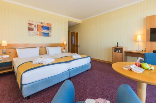 a hotel room with a bed and a table and chairs at Strand-Hotel Hübner in Warnemünde