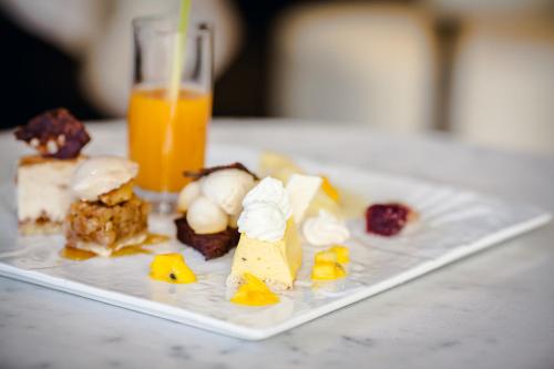 a plate of desserts and a glass of orange juice at Hôtel Logis Le Bourbon in Yssingeaux