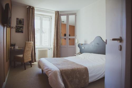 Yssingeaux的住宿－Hôtel Logis Le Bourbon，一间卧室配有一张床和一张桌子及椅子