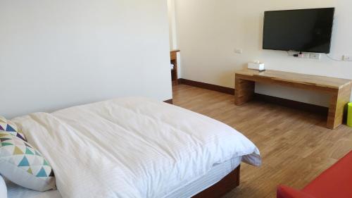 a bedroom with a bed and a tv on a wall at Shui Bu Zi Farmhouse in Puli