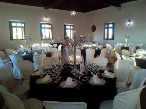 a room filled with tables and white chairs with glasses at Quinta dos Álamos Agroturismo in Golegã