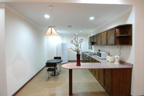 una cocina con una mesa con un jarrón de flores. en Ramee Suite Apartment 4, en Manama