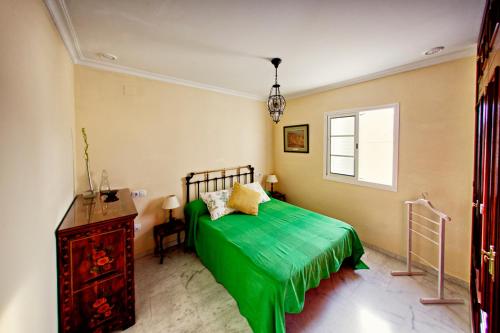 Un dormitorio con una cama verde y una ventana en El Ático de Cervantes, en Cádiz