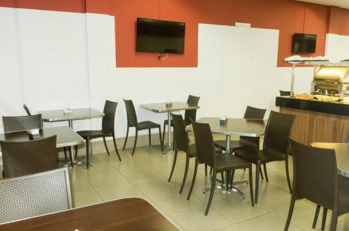 a dining room with tables and chairs and a tv on the wall at Stop Inn Antonio Carlos in Belo Horizonte