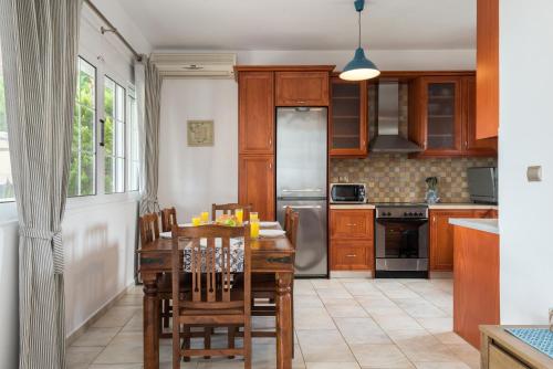 una cocina con armarios de madera, mesa y sillas en Villa AnnaMaria en Skala Kefalonias