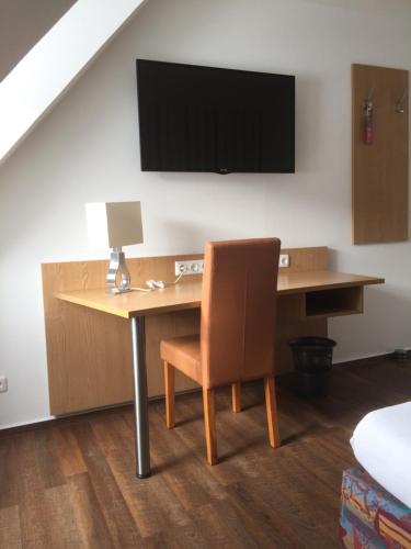 a desk with a chair and a television on a wall at Hotel Wittgensteiner Hof in Bad Laasphe