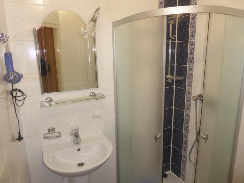 a bathroom with a sink and a shower with a mirror at Мини-отель "Ольга" in Truskavets