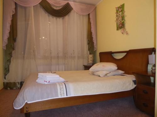 a bedroom with a bed with white sheets and a window at Мини-отель "Ольга" in Truskavets