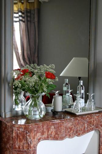 une table avec un vase de fleurs et un miroir dans l'établissement Le Clos des Pommiers, à Blainville-sur-Mer