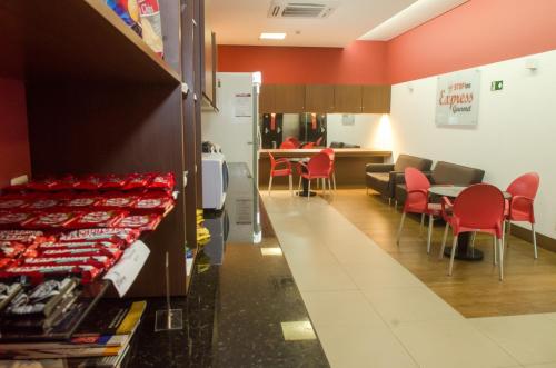 a restaurant with red chairs and a table and a counter at Stop Inn Antonio Carlos in Belo Horizonte