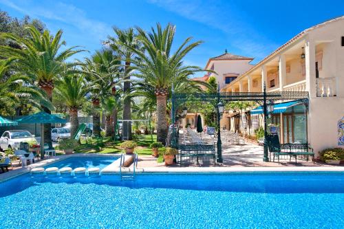 einem Pool mit einer Person, die auf einem Stuhl neben einem Gebäude sitzt in der Unterkunft Hotel Rosa in Denia