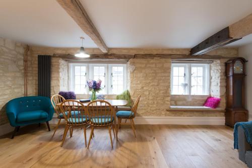 a dining room with a table and chairs and windows at Upper Flat, The Manse, Painswick in Painswick