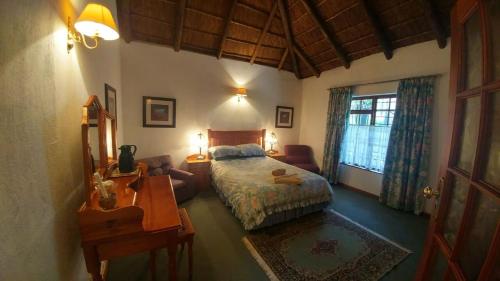Oaktree Lodge Guest House في Kyalami: غرفة نوم بسرير ومكتب وسرير ونافذة