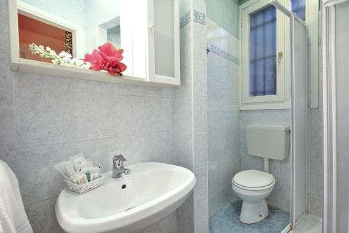 La salle de bains est pourvue d'un lavabo blanc et de toilettes. dans l'établissement Antico Fiore Apartments, à Venise