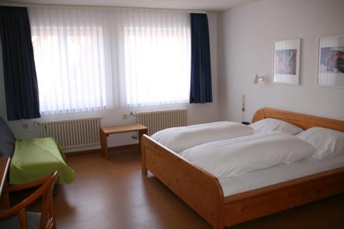 a bedroom with two beds and a table and windows at Sontheimer Wirtshäusle in Sontheim im Stubental
