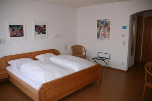 1 dormitorio con cama de madera con sábanas blancas en Sontheimer Wirtshäusle, en Sontheim im Stubental