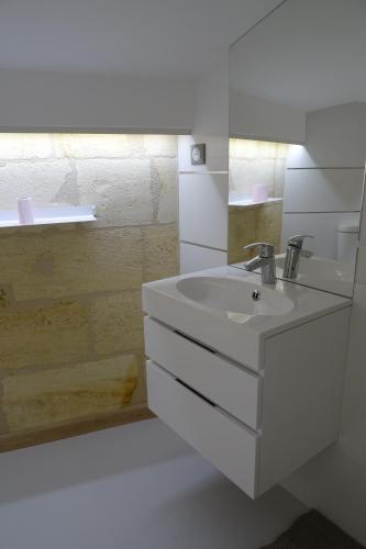 une salle de bain blanche avec un lavabo et une douche dans l'établissement 12 Rue des Ecoles, à Saint-Émilion