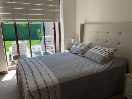1 dormitorio con 1 cama y balcón con sillas en Casa en Condominio Costa Pucón, en Pucón