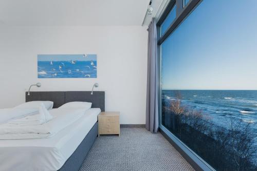 a bedroom with a large window with a view of the ocean at Apartamenty Laguna Boulevard by Renters Prestige in Ustronie Morskie