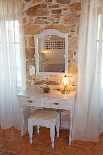 a white dressing table with a mirror and a lamp at Saint George Valsamitis Superior in Katapola