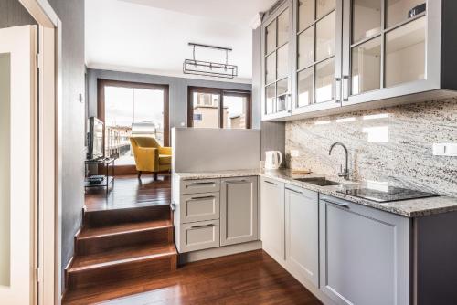 a kitchen with white cabinets and wood floors at Triton Park Apartments in Warsaw