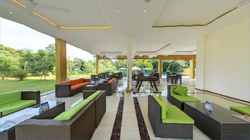 een open woonkamer met groene stoelen en tafels bij Cassandra Culture Resort in Sigiriya