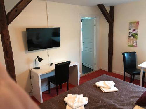 Zimmer mit einem Schreibtisch, einem TV und Stühlen in der Unterkunft Hotel Frøslev Kro in Padborg