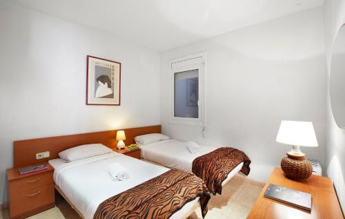 una camera d'albergo con due letti e una scrivania di Apartamentos Calvet a Barcellona