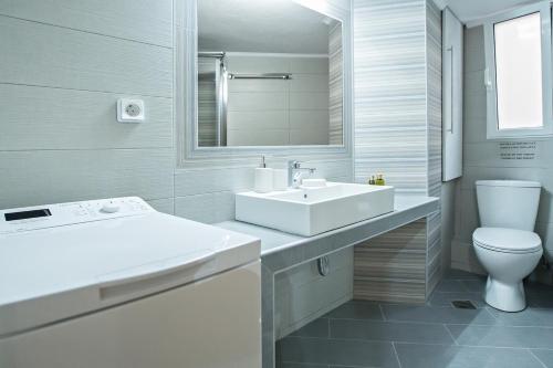 a white bathroom with a sink and a toilet at Paradise Apartment in Peiraiki in Piraeus