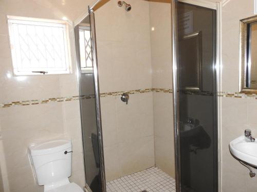 a bathroom with a shower and a toilet and a sink at Rose of Sharon in Amanzimtoti