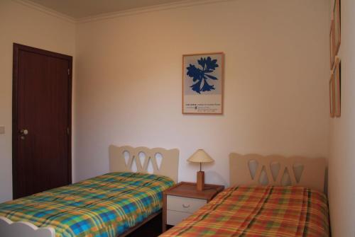 a bedroom with a bed and a table with a lamp at Vila Da Praia in Campo de Baixo