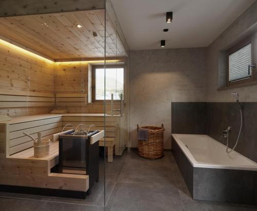 een badkamer met een bad, een wastafel en een bad bij Hotel Chalets Grosslehen in Fieberbrunn