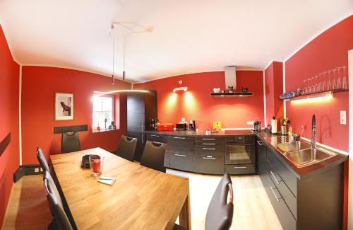 eine Küche mit roten Wänden und einem Holztisch mit Stühlen in der Unterkunft Gästehaus-Fulda in Fulda