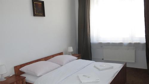 a bedroom with a bed with white sheets and a window at Hotel Olimpijski in Tarnowskie Góry