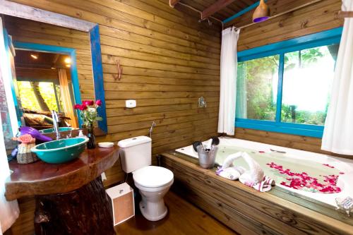 uma casa de banho em madeira com uma banheira, um WC e um lavatório. em Pousada Refúgio das Montanhas em Praia Grande